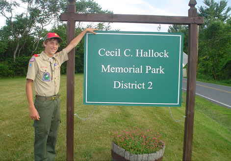 Scout standing at Cecil C. Hallock Memorial Park Sign